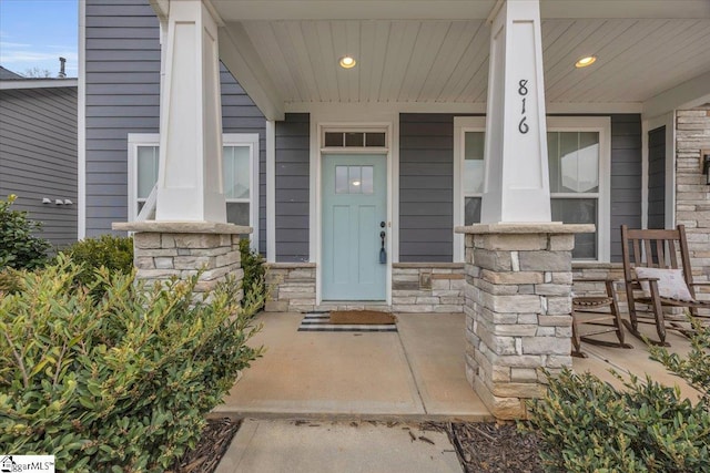 view of exterior entry featuring stone siding and covered porch