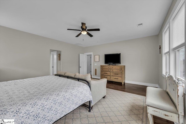 bedroom with visible vents, baseboards, wood finished floors, and a ceiling fan