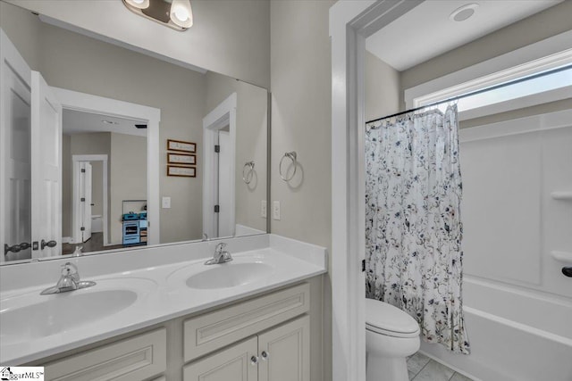 bathroom featuring tile patterned flooring, double vanity, toilet, and a sink