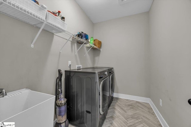 laundry area with a sink, baseboards, separate washer and dryer, and laundry area