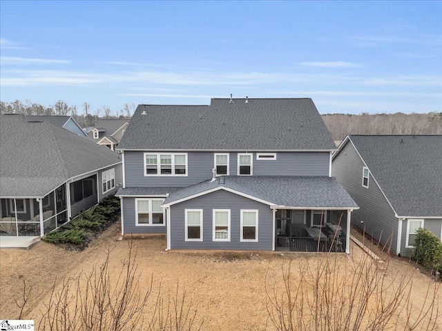 rear view of property featuring a sunroom and roof with shingles