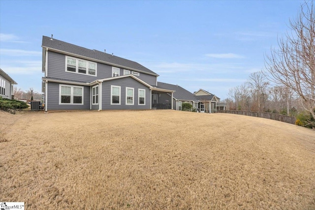 rear view of house with a yard, central AC, and fence