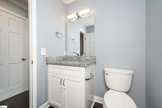 bathroom featuring baseboards, toilet, and vanity