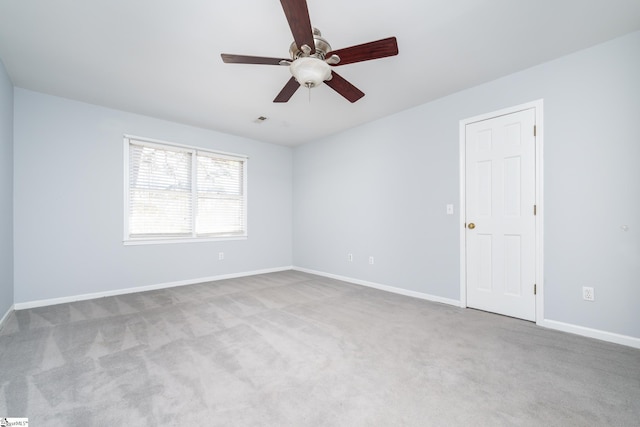 carpeted empty room featuring a ceiling fan and baseboards