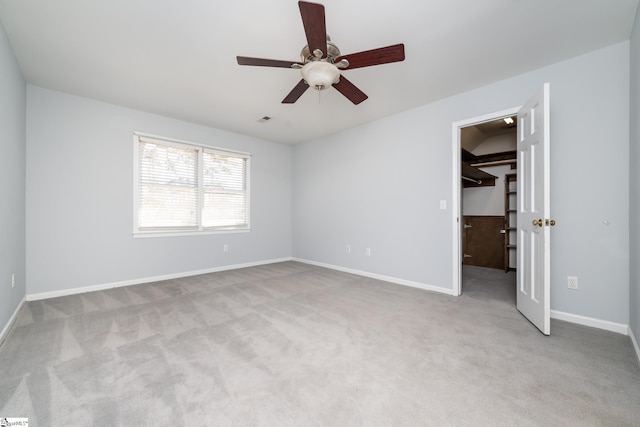 unfurnished bedroom featuring visible vents, baseboards, carpet floors, ceiling fan, and a spacious closet