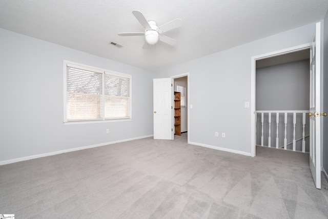 unfurnished bedroom with visible vents, a textured ceiling, carpet, baseboards, and ceiling fan