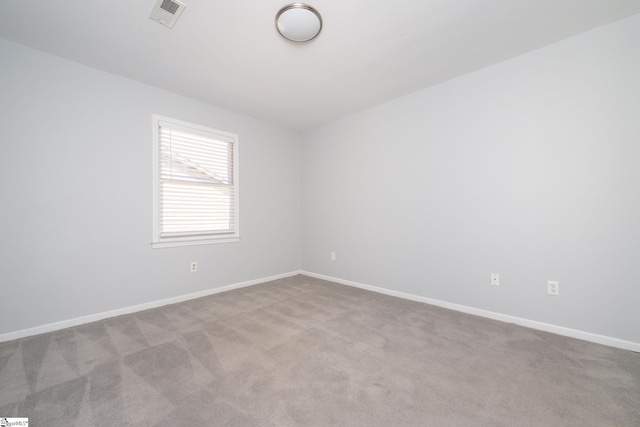 empty room featuring carpet, visible vents, and baseboards