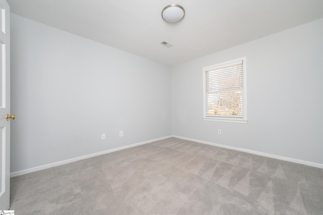 carpeted spare room with visible vents and baseboards