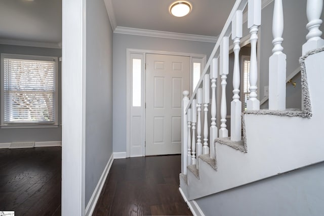 foyer entrance featuring visible vents, crown molding, baseboards, and wood finished floors