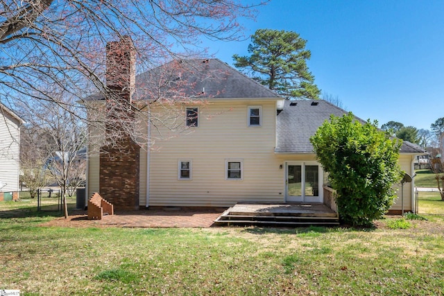 back of house featuring a gate, fence, a yard, a shingled roof, and a chimney