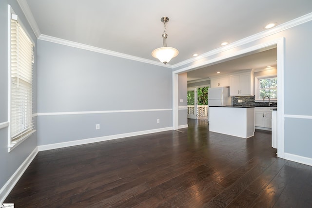 unfurnished living room with a sink, baseboards, dark wood finished floors, and ornamental molding