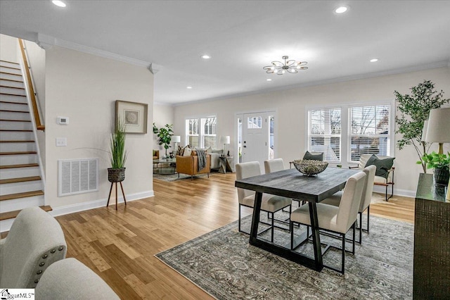 dining space featuring stairway, light wood-style flooring, visible vents, and ornamental molding