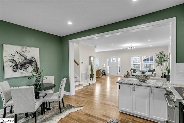 kitchen with visible vents, white cabinetry, a peninsula, high end stainless steel range oven, and light wood-type flooring