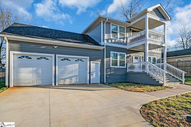 view of front of home with board and batten siding, roof with shingles, driveway, a balcony, and an attached garage