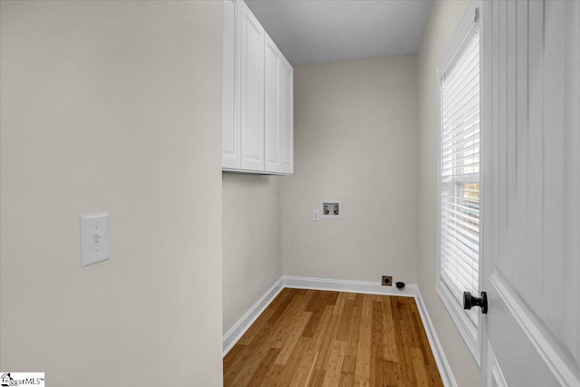 laundry room with hookup for a washing machine, cabinet space, baseboards, and light wood finished floors