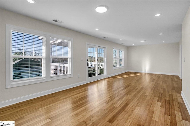 empty room with light wood-style flooring, recessed lighting, visible vents, and baseboards