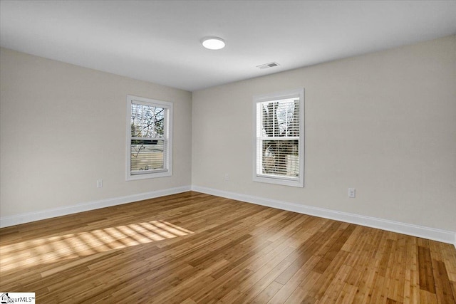 spare room with light wood-style floors, visible vents, and baseboards