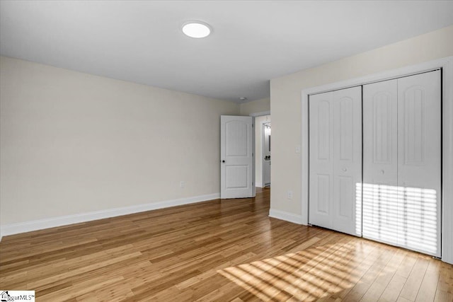 unfurnished bedroom with light wood-style floors, baseboards, and a closet