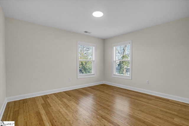 spare room with baseboards, visible vents, and light wood finished floors