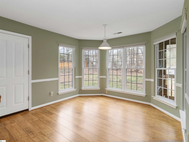 unfurnished dining area with light wood-style flooring, baseboards, and visible vents