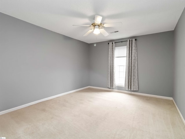 carpeted empty room with a ceiling fan, visible vents, and baseboards