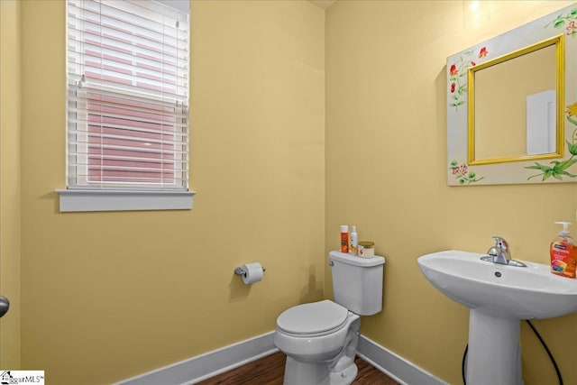 bathroom with wood finished floors, toilet, baseboards, and a sink