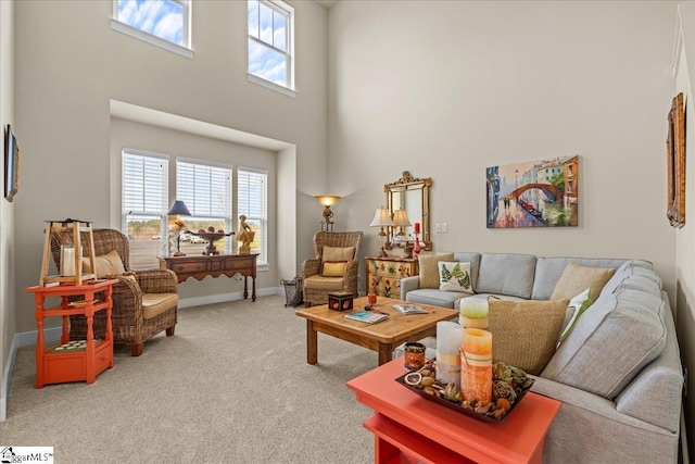 living area featuring a wealth of natural light, baseboards, light carpet, and a high ceiling