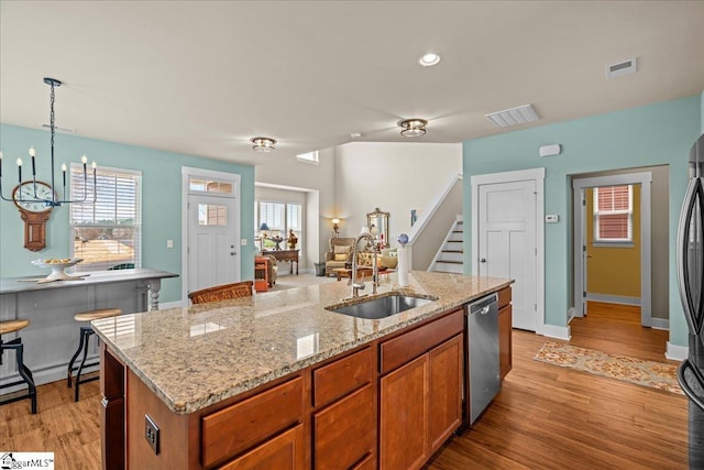 kitchen featuring stainless steel dishwasher, light wood-type flooring, visible vents, and a sink