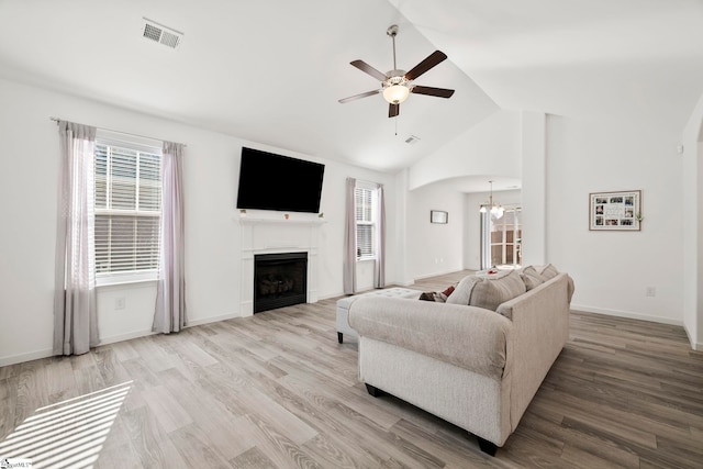 living area featuring a wealth of natural light, visible vents, ceiling fan with notable chandelier, and vaulted ceiling