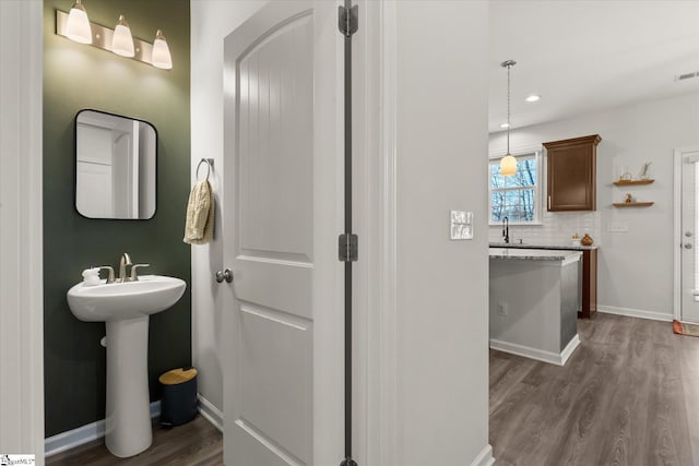 bathroom featuring decorative backsplash, wood finished floors, baseboards, and a sink