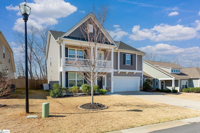 view of front facade featuring driveway, stone siding, fence, an attached garage, and a balcony