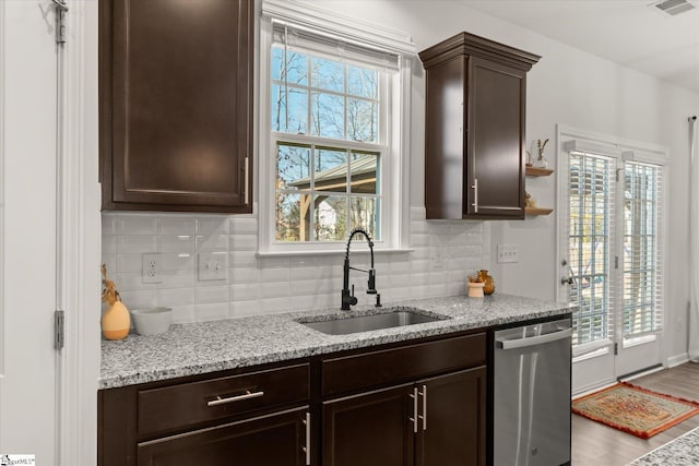 kitchen with stainless steel dishwasher, dark brown cabinetry, a wealth of natural light, and a sink