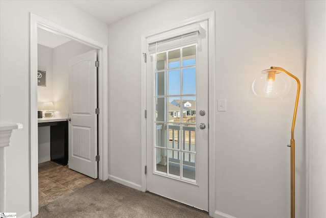 doorway featuring baseboards and carpet