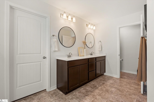 full bath with double vanity, baseboards, and a sink