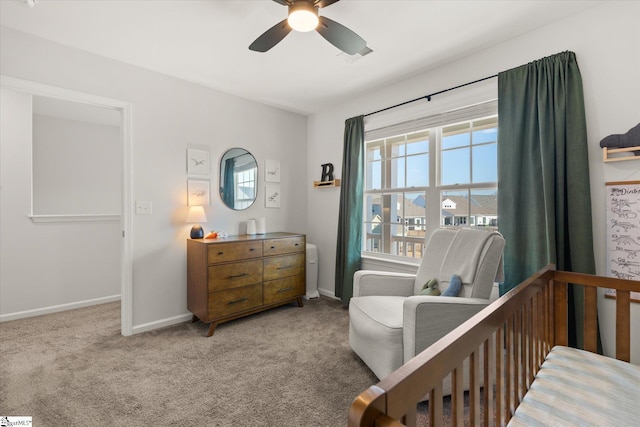 bedroom with a crib, carpet, baseboards, and ceiling fan