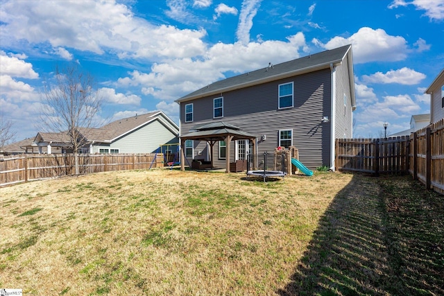 rear view of house with a gazebo, a yard, and a fenced backyard