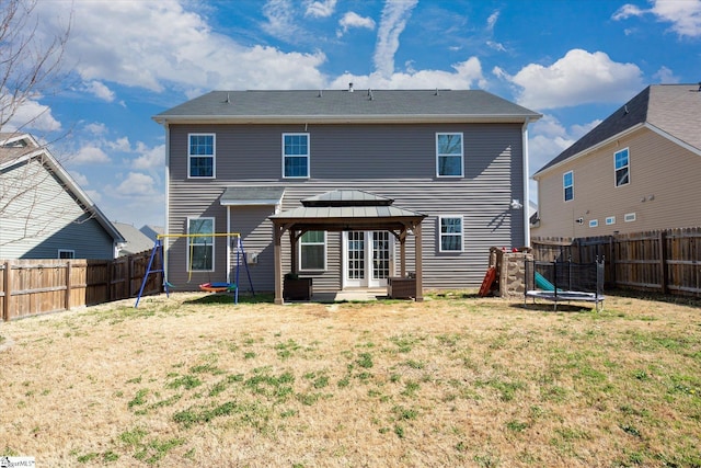 back of property with a playground, a trampoline, a gazebo, a fenced backyard, and a yard