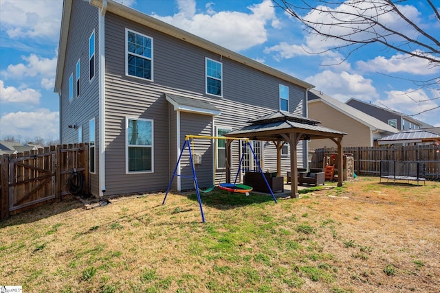 rear view of house featuring a gazebo, a lawn, and a fenced backyard