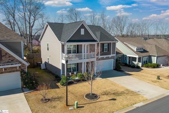 view of front of home featuring covered porch, a shingled roof, concrete driveway, a front lawn, and a garage