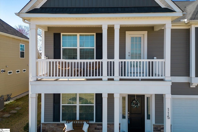 view of exterior entry with board and batten siding, a balcony, covered porch, and stone siding