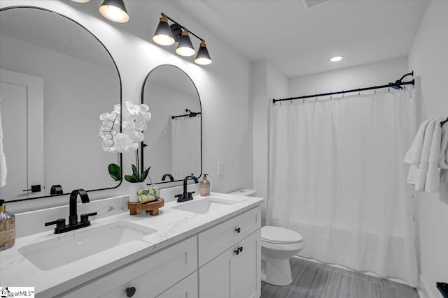 full bathroom featuring double vanity, toilet, shower / tub combo with curtain, and a sink