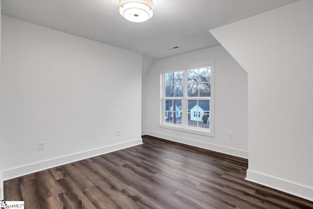 unfurnished room with dark wood-style floors, visible vents, and baseboards