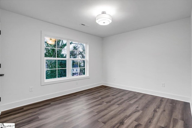 empty room with visible vents, baseboards, and dark wood-style flooring