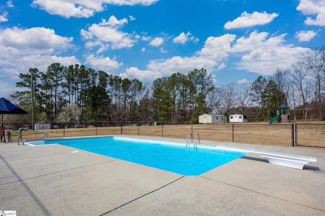 view of swimming pool with a diving board, a fenced in pool, playground community, and fence