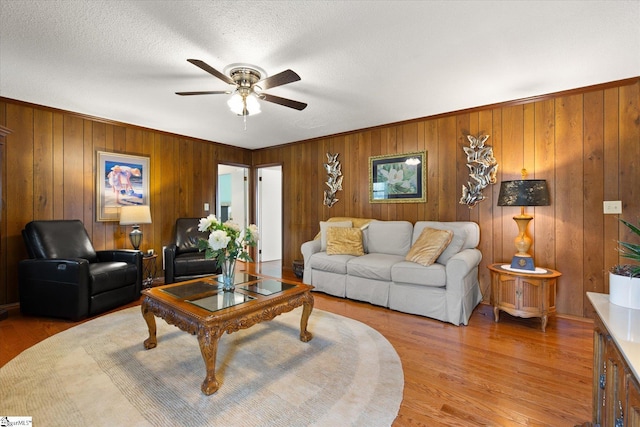 living room featuring light wood-style floors, a ceiling fan, and a textured ceiling