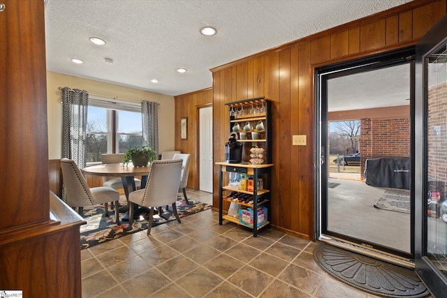 dining room with plenty of natural light, recessed lighting, wood walls, and a textured ceiling