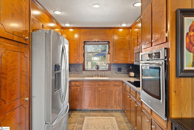 kitchen featuring brown cabinetry, a sink, light countertops, appliances with stainless steel finishes, and tasteful backsplash