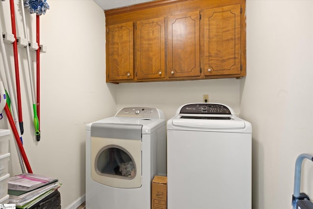 clothes washing area with cabinet space and washing machine and dryer