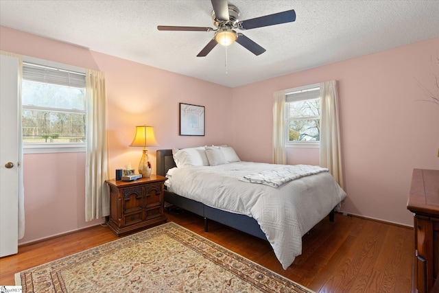 bedroom with a textured ceiling, ceiling fan, and wood finished floors