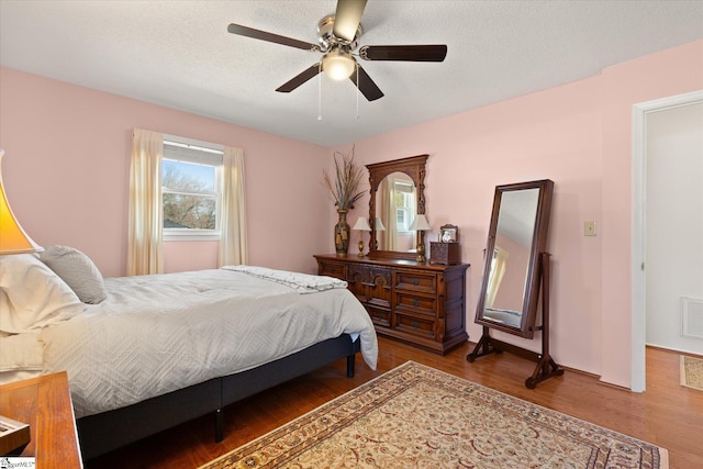 bedroom featuring visible vents, a textured ceiling, ceiling fan, and wood finished floors